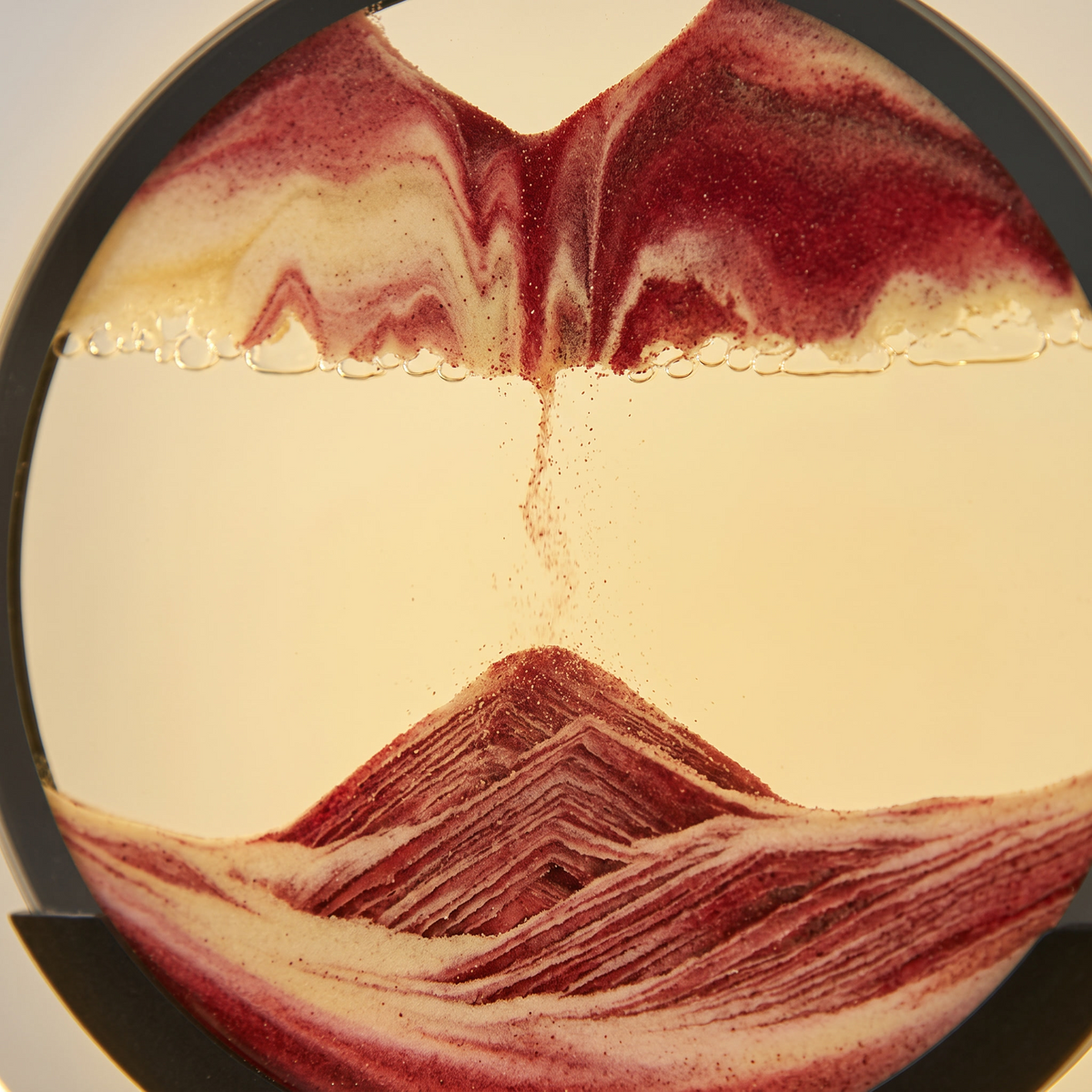Close up of the sand settling into layered ridges behind the glass of the Dune lamp