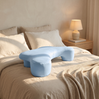 Cradle side sleeper pillow on a made bed in a calm neutral bedroom