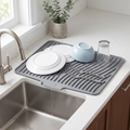 Rill gray silicone dish drying mat by the sink, draining water from washed dishes